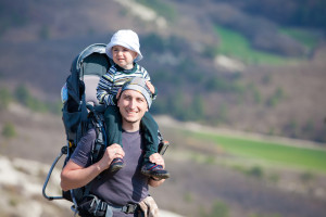 Father is hiking with the 1.5 year baby in baby carrier